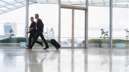 Businessmen walking and pulling suitcase in airport Stock Photo - Premium Royalty-Free, Code: 6113-08943709