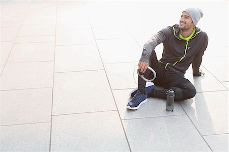 simsearch:693-07672615,k - Smiling male runner resting, holding headphones and looking away Stock Photo - Premium Royalty-Free, Code: 6113-08943731
