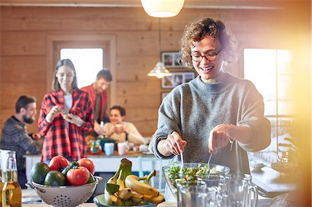Woman tossing salad for friends in cabin Stock Photo - Premium Royalty-Free, Code: 6113-08947389