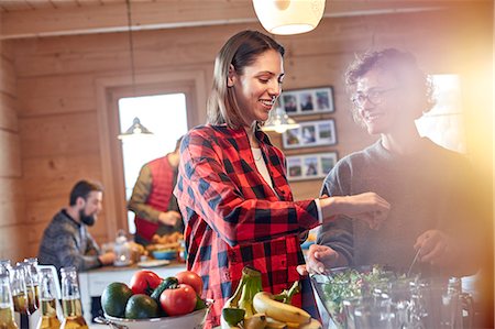 Friends tossing salad in cabin Stock Photo - Premium Royalty-Free, Code: 6113-08947391
