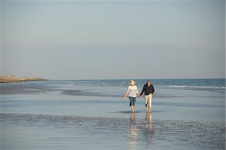 simsearch:6113-07589470,k - Mature couple holding hands walking in sunny ocean beach surf Stock Photo - Premium Royalty-Free, Code: 6113-08985757