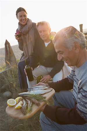 simsearch:6113-07147024,k - Mature friends drinking wine and barbecuing fish on sunset beach Stock Photo - Premium Royalty-Free, Code: 6113-08985776