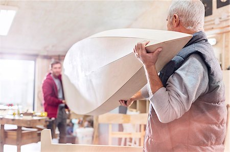 father holds son - Male carpenters carrying wood boat in workshop Stock Photo - Premium Royalty-Free, Code: 6113-08985863