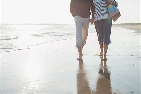simsearch:6113-07589470,k - Affectionate barefoot mature couple walking, holding hands in sunny ocean beach surf Stock Photo - Premium Royalty-Free, Code: 6113-08985818