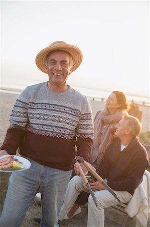 simsearch:649-07438003,k - Portrait smiling senior man barbecuing with friends on sunset beach Stock Photo - Premium Royalty-Free, Code: 6113-08985825