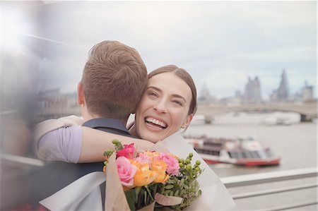 simsearch:6108-06166561,k - Happy, grateful woman receiving flower bouquet, hugging boyfriend on urban waterfront Foto de stock - Sin royalties Premium, Código: 6113-08985973