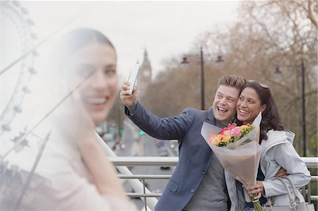 simsearch:6108-06166561,k - Enthusiastic couple with flower bouquet taking selfie with camera phone on urban bridge, London, UK Foto de stock - Sin royalties Premium, Código: 6113-08985976