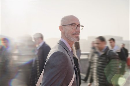 simsearch:6113-06909277,k - Serious, pensive businessman walking on busy urban pedestrian bridge Stock Photo - Premium Royalty-Free, Code: 6113-08985987