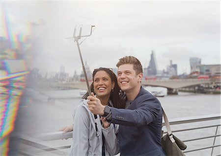simsearch:6113-06498180,k - Couple tourists taking selfie with camera phone selfie stick at Thames River waterfront, London, UK Stock Photo - Premium Royalty-Free, Code: 6113-08986056