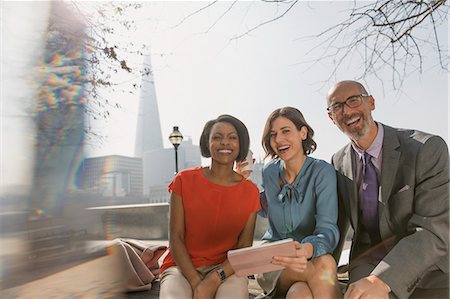 simsearch:649-06040627,k - Portrait smiling business people using digital tablet in sunny urban park Stock Photo - Premium Royalty-Free, Code: 6113-08986060
