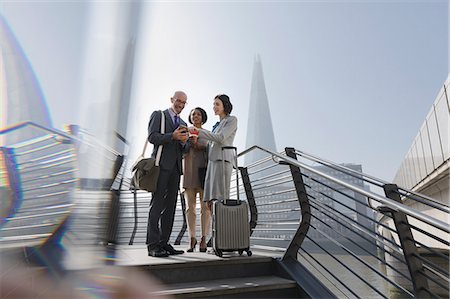 simsearch:6122-07706325,k - Business people with suitcase using digital tablet on sunny waterfront, London, UK Stock Photo - Premium Royalty-Free, Code: 6113-08986061