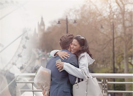 simsearch:6108-06166423,k - Smiling couple hugging, boyfriend surprising girlfriend with flowers on urban bridge, London, UK Foto de stock - Sin royalties Premium, Código: 6113-08986065