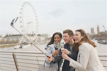 simsearch:6113-07648679,k - Smiling friend tourists celebrating, toasting champagne and taking selfie with selfie stick near Millennium Wheel, London, UK Stock Photo - Premium Royalty-Free, Code: 6113-08986076