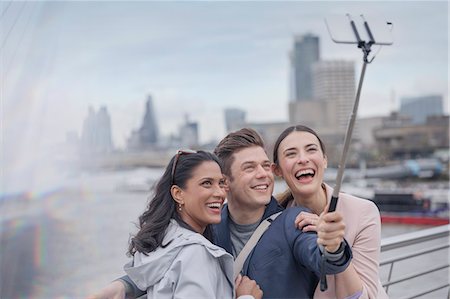 simsearch:6113-07648679,k - Enthusiastic, smiling friend tourists taking selfie with selfie stick on urban bridge, London, UK Stock Photo - Premium Royalty-Free, Code: 6113-08986095