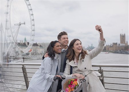 simsearch:6113-06498180,k - Smiling, happy friends taking selfie with selfie stick on bridge near Millennium Wheel, London, UK Stock Photo - Premium Royalty-Free, Code: 6113-08986098