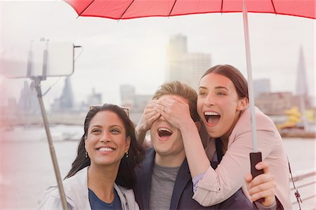 simsearch:6113-06899628,k - Playful friend tourists with umbrella taking selfie with camera phone selfie stick on bridge, London, UK Stock Photo - Premium Royalty-Free, Code: 6113-08986006