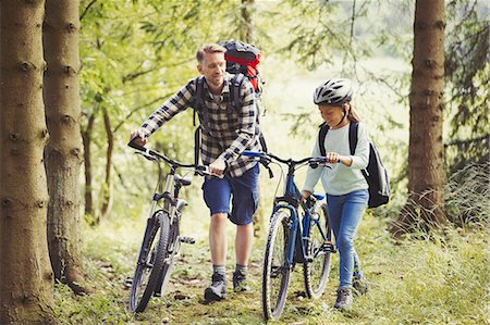 simsearch:614-06623416,k - Father and daughter with backpacks walking mountain bikes in woods Stock Photo - Premium Royalty-Free, Code: 6113-08909848