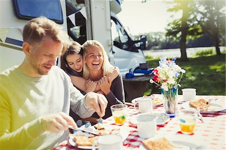 Happy family hugging and eating breakfast outside sunny motor home Stock Photo - Premium Royalty-Free, Code: 6113-08909849