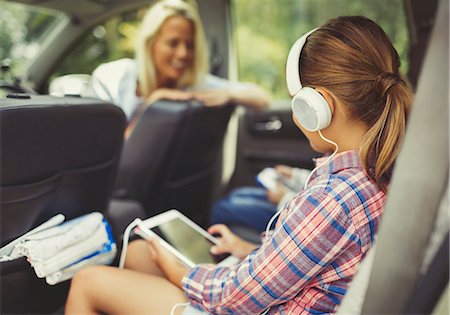 enjoying music - Girl with headphones using digital tablet watching video in back seat of car Stock Photo - Premium Royalty-Free, Code: 6113-08909851
