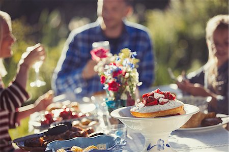 family lunches in the backyard - Family enjoying strawberry cake at sunny garden party patio table Stock Photo - Premium Royalty-Free, Code: 6113-08909857