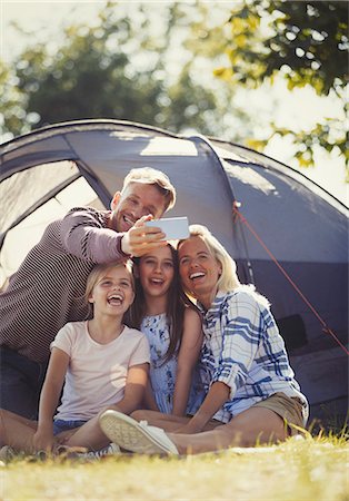 simsearch:649-08232457,k - Happy family taking selfie with camera phone outside sunny campsite tent Stock Photo - Premium Royalty-Free, Code: 6113-08909875