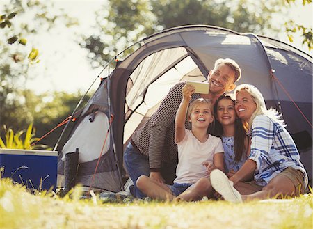 simsearch:649-08232457,k - Family taking selfie with camera phone outside tent at sunny campsite Stock Photo - Premium Royalty-Free, Code: 6113-08909949