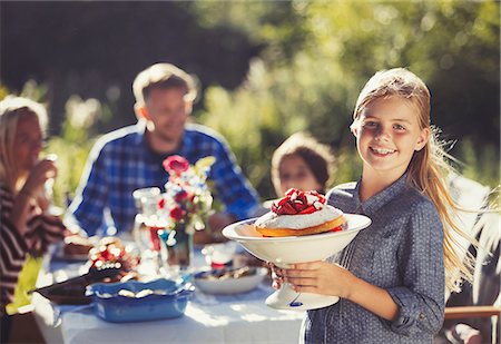 simsearch:6113-07242497,k - Portrait smiling girl serving strawberry cake to family at sunny garden party patio table Foto de stock - Sin royalties Premium, Código: 6113-08909967