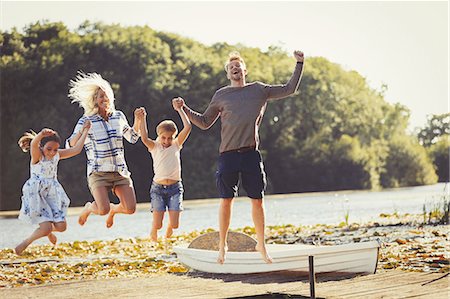 Exuberant family jumping on sunny lake dock Photographie de stock - Premium Libres de Droits, Code: 6113-08909915