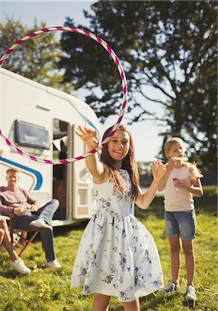 Portrait playful girl spinning plastic hoop outside sunny motor home Foto de stock - Sin royalties Premium, Código: 6113-08909937