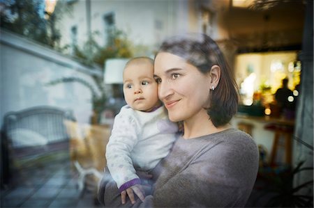 simsearch:6113-06909277,k - Smiling mother holding baby daughter at window Stock Photo - Premium Royalty-Free, Code: 6113-08910043