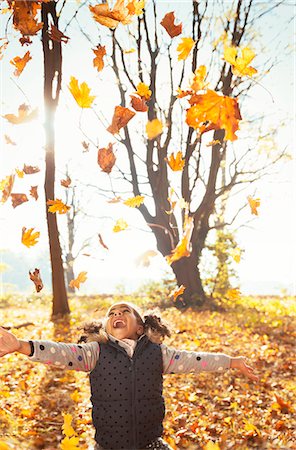 Playful girl throwing leaves overhead in sunny autumn park Stock Photo - Premium Royalty-Free, Code: 6113-08910095