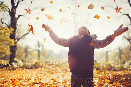 simsearch:649-07647801,k - Playful girl throwing autumn leaves overhead in sunny park Stock Photo - Premium Royalty-Free, Code: 6113-08910163