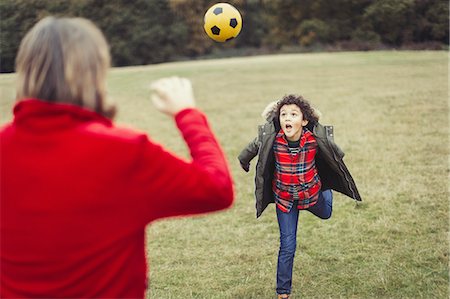 running in the fall - Father cheering for playful son running in park Stock Photo - Premium Royalty-Free, Code: 6113-08910115