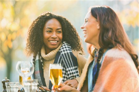 simsearch:6113-07147381,k - Smiling young women friends drinking beer at autumn sidewalk cafe Stock Photo - Premium Royalty-Free, Code: 6113-08927779