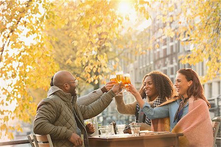 simsearch:6113-07543030,k - Smiling friends toasting beer glasses at autumn sidewalk cafe Stock Photo - Premium Royalty-Free, Code: 6113-08927731