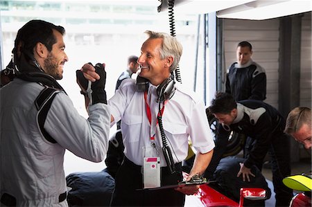 driver (vehicle, male) - Manager and formula one driver celebrating, handshaking in repair garage Stock Photo - Premium Royalty-Free, Code: 6113-08927893