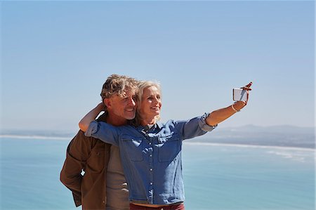 simsearch:6113-06498180,k - Affectionate senior couple taking selfie overlooking sunny ocean view Stock Photo - Premium Royalty-Free, Code: 6113-08927968