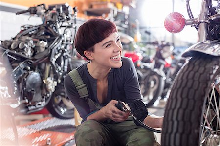 simsearch:6113-08722278,k - Enthusiastic female motorcycle mechanic repairing motorcycle in workshop Stock Photo - Premium Royalty-Free, Code: 6113-08927995