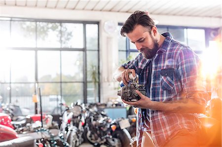 Motorcycle mechanic greasing engine part in workshop Stock Photo - Premium Royalty-Free, Code: 6113-08927998