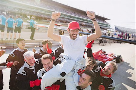 simsearch:6113-07648679,k - Formula one racing team carrying driver on shoulders, celebrating victory on sports track Stock Photo - Premium Royalty-Free, Code: 6113-08927906