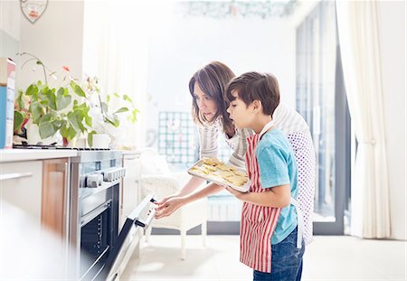 Mother and son baking, placing cookies in oven in kitchen Photographie de stock - Premium Libres de Droits, Code: 6113-08928043