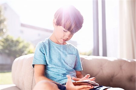simsearch:6113-06908842,k - Curious boy using cell phone in sunny living room Stock Photo - Premium Royalty-Free, Code: 6113-08928041