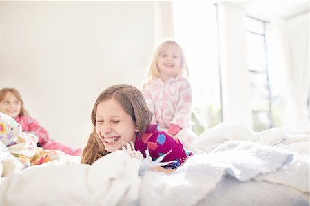 Laughing sisters playing on bed Stock Photo - Premium Royalty-Free, Code: 6113-08928068