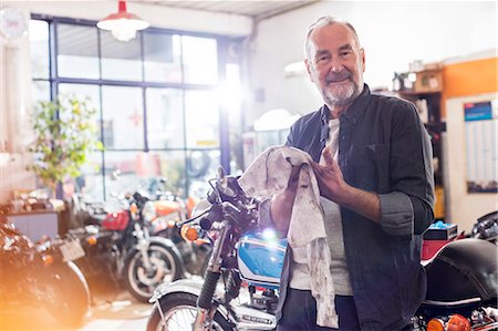 simsearch:6113-08722278,k - Portrait smiling senior male motorcycle mechanic wiping hands on rag in workshop Stock Photo - Premium Royalty-Free, Code: 6113-08928017