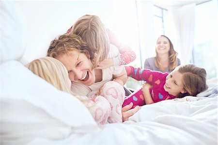 daddy tickles daughter - Playful father and daughters tickling on bed Stock Photo - Premium Royalty-Free, Code: 6113-08928031