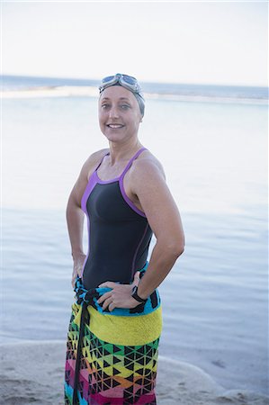 swimming, happy - Portrait smiling, confident female open water swimmer wrapped in towel on ocean beach Stock Photo - Premium Royalty-Free, Code: 6113-09058373