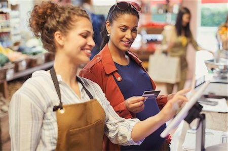 debit card - Female cashier helping pregnant woman paying with credit card at grocery store cash register Stock Photo - Premium Royalty-Free, Code: 6113-09058443