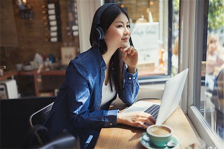 simsearch:6113-07565805,k - Pensive young woman listening to music with headphones at laptop and drinking coffee in cafe window Stock Photo - Premium Royalty-Free, Code: 6113-09058543