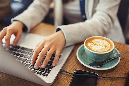 simsearch:695-05771662,k - Hands of young woman using laptop, drinking cappuccino in cafe Stock Photo - Premium Royalty-Free, Code: 6113-09058502