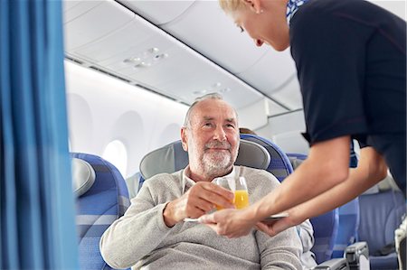 flying happy woman images - Flight attendant serving orange juice to man on airplane Stock Photo - Premium Royalty-Free, Code: 6113-09059153